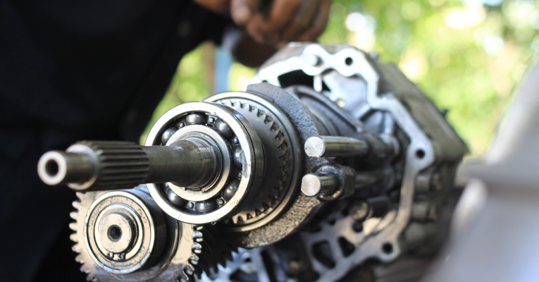  Hand of a car mechanic, fixing the disassembled gear parts of a transmission.
